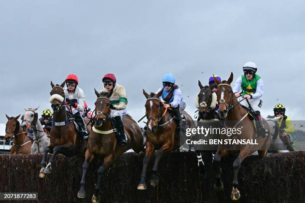 Horses jump a fence during the Ultima Handicap Chase on the first day of the Cheltenham Festival at Cheltenham Racecourse, in Cheltenham, western...
