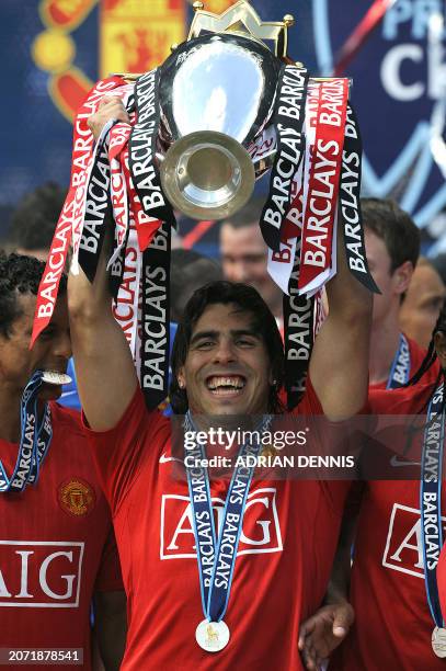 Manchester United's Argentinian forward Carlos Tevez celebrates with the English Premier League trophy after they clinch the title with a 0-0 draw...