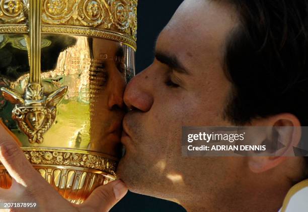 Switzerland's Roger Federer kisses the trophy after winning against in the men's final match on Day 13 at the 2009 Wimbledon tennis championships at...