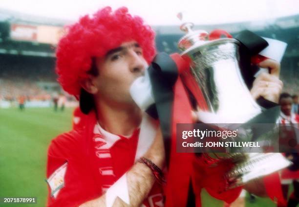 Manchester United player Eric Cantona wearing a red wig carries the English football cup on May 15, 1994 in Wembley as he celebrates the victory of...