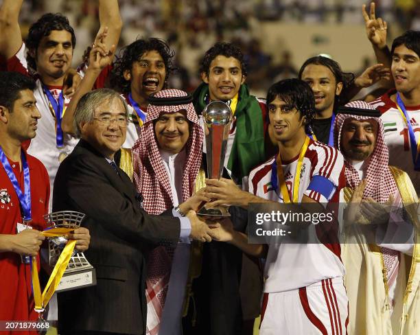 Emirati captain Hamdan Ismail receives the trophy from Junji Ogura , chairman of the Organising Committee for AFC Youth Competitions, following the...