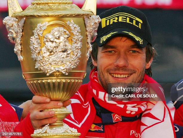 French rally driver Sebastien Loeb of the Citroen Total WRT rally team celebrates as he holds up the trophy after winning the World Rally...