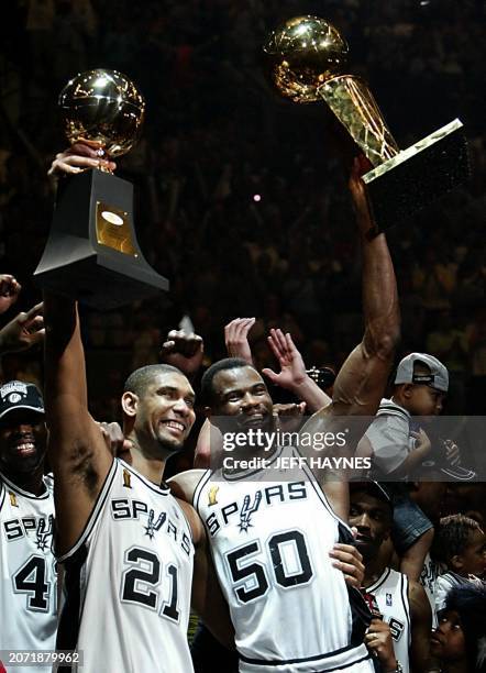 Series MVP Tim Duncan and David Robinson of the San Antonio Spurs hold-up the MVP Trophy and the Larry O'Brian Championship trophy after beating the...