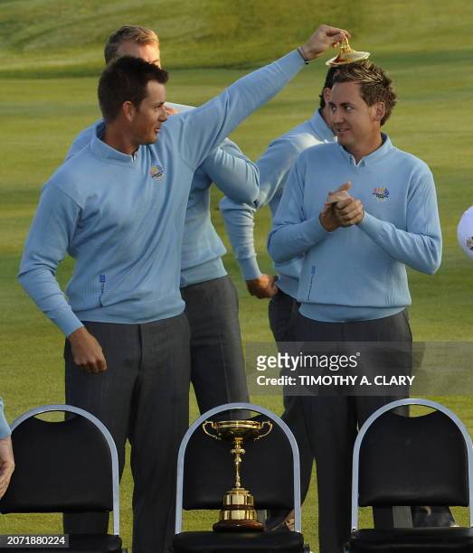 Henrik Stenson of Sweden places the lid of the Ryder Cup on the head of Ian Poulter of England as Team Europe poses for their team photo before the...