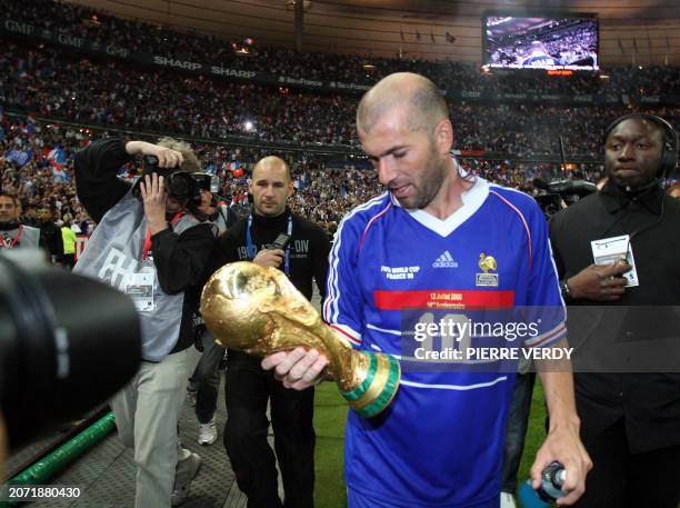 French player Zinedine Zidane , holding the world Cup trophee, salutes the crowd after the football exhibition match between France's 1998 World Cup...