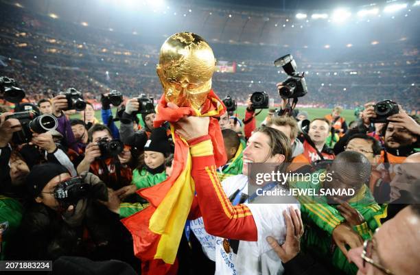 Spain's defender Sergio Ramos holds up the trophy, the base of it wrapped in the Spanish national flag, during the award ceremony following their...