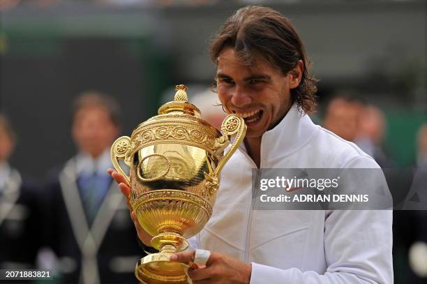 Spain's Rafael Nadal bites the Wimbledon Trophy as he poses for pictures after beating Czech Republic's Tomas Berdych 6-3, 7-5, 6-4, in the Men's...