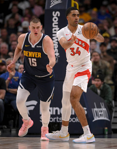 Jontay Porter of the Toronto Raptors pushes the ball in transition ahead of Nikola Jokic of the Denver Nuggets during the first quarter at Ball Arena...