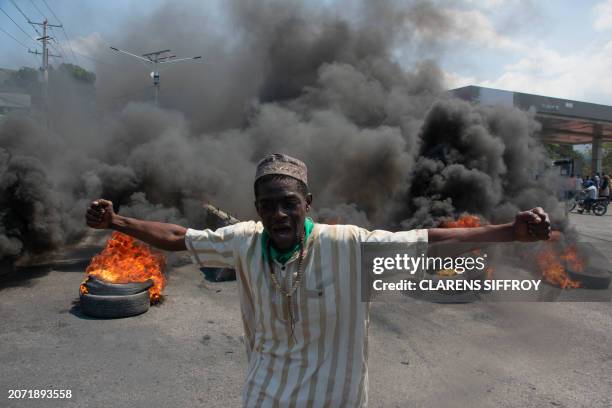 Protester reacts while tires burn in the street during a demonstration following the resignation of its Prime Minister Ariel Henry, in...
