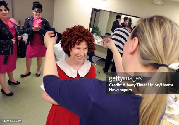 Makeup artist Ann Aumick, right, helps Cathy Woodruff put on her wig in the dressing room during rehearsal night for this year's Legislative...