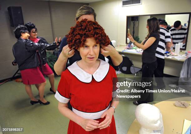 Makeup artist Ann Aumick helps Cathy Woodruff put on her wig in the dressing room during rehearsal night for this year's Legislative Correspondents...