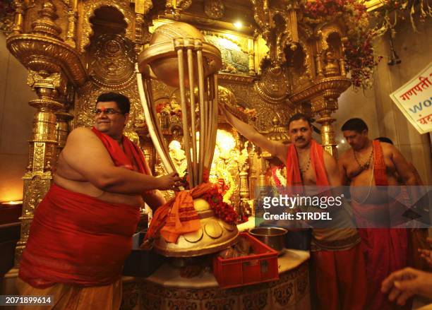 Indian Hindu priests hold a replica of the Cricket World Cup trophy during a special prayer organised to seek blessings of Hindu god Lord Ganesha for...