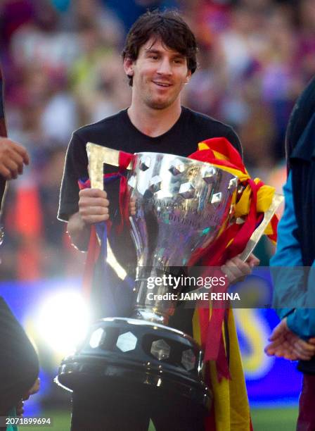 Barcelona's Argentinian forward Lionel Messi holds the Spanish League winner trophy during a celebration with supporters at the Camp Nou stadium in...