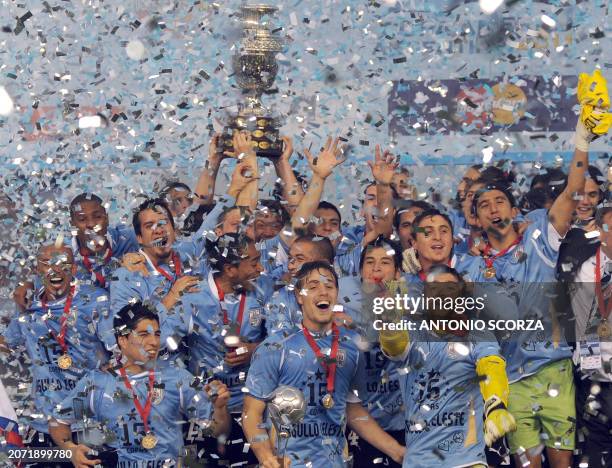 Uruguayan defender Diego Lugano raises the trophy and celebrates with teammates at the end of the 2011 Copa America football tournament final against...