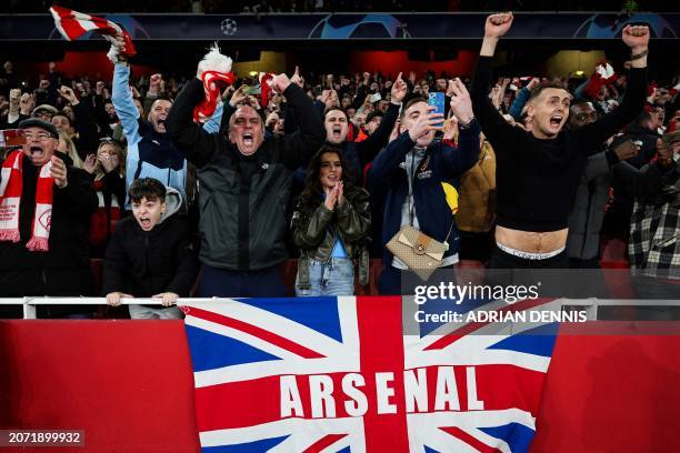 Arsenal's supporters celebrate during the penalty shoot-out session of the UEFA Champions League last 16 second leg football match between Arsenal...