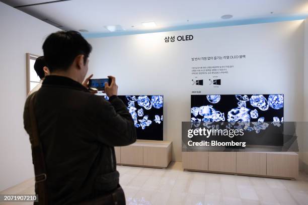 Visitor takes a photograph of Samsung Electronics Co. New OLED televisions at a media event in Seoul, South Korea, on Thursday, March 13, 2024....