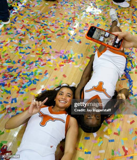 Texas Longhorns cheerleaders pose for photos after defeating the Iowa State Cyclones in the Big 12 Women's Basketball Tournament championship game at...