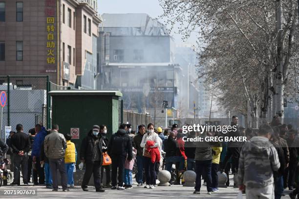 People gather as they watch rescue operations at the scene of a suspected gas explosion in Sanhe, in China's northern Hebei province on March 13,...