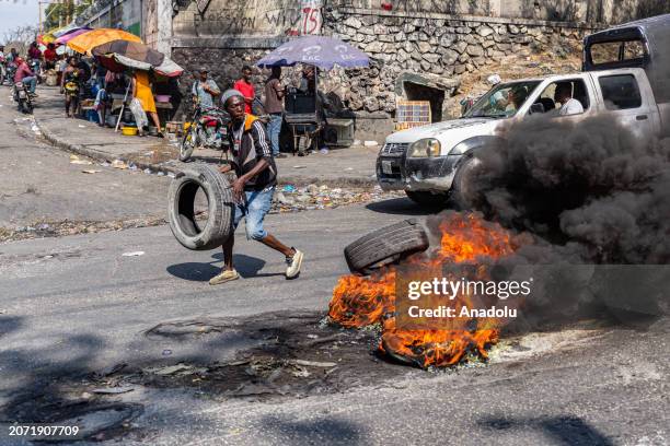 Man sets a tire on fire during a demonstration against CARICOM for the decision following the resignation of Haitian Prime Minister Ariel Henry as...