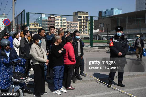 People gather at a police line opposite to the site of a suspected gas explosion in Sanhe, in China's northern Hebei province on March 13, 2024. A...