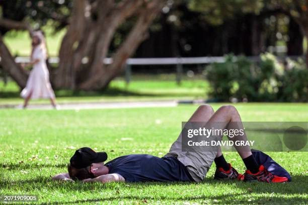 Man rests with his cap over his face at the Royal Botanical Gardens on World Sleep Day, which aims to raise awareness of the importance of sleep and...