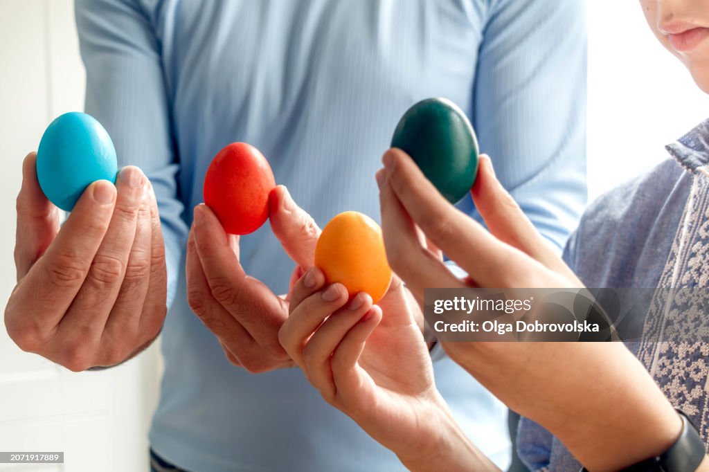 Father and son holding dyed Easter eggs in hands