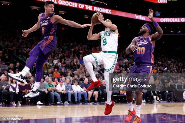 Derrick White of the Boston Celtics attempts a layup against Grayson Allen and Royce O'Neale of the Phoenix Suns during the first half at Footprint...