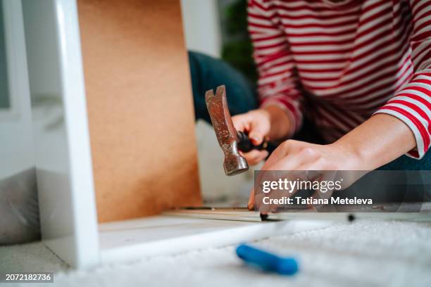 furniture assembly with hammer: handywoman assembling nightstand in new apartment - woman hammer stock pictures, royalty-free photos & images