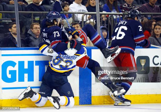 Jake Neighbours of the St. Louis Blues checks Matt Rempe of the New York Rangers during the third period at Madison Square Garden on March 09, 2024...