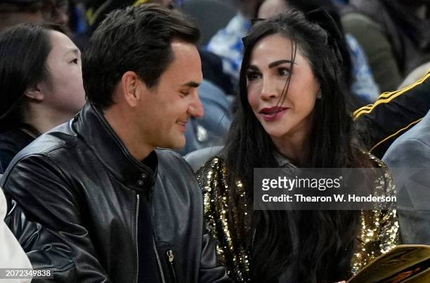 Tennis legend Roger Federer and Nicole Curran, wife of Golden State Warriors owner Joe Lacob, sit court side during the game between the San Antonio...