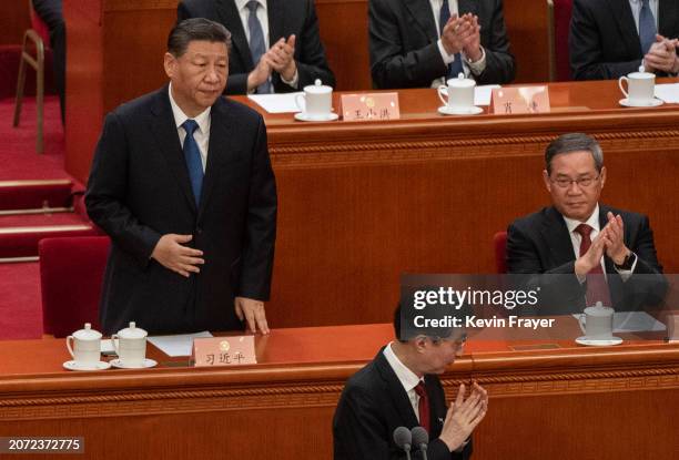 Chinese President Xi Jinping stands as he is recognized and applauded by Premier Li Qiang, right, and Chairman of the Chinese People's Political...