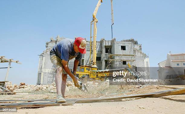 Palestinian labourer cuts steel reinforcing rods for a new housing project on June 11, 2003 in the West Bank Jewish settlement of Ariel. According to...