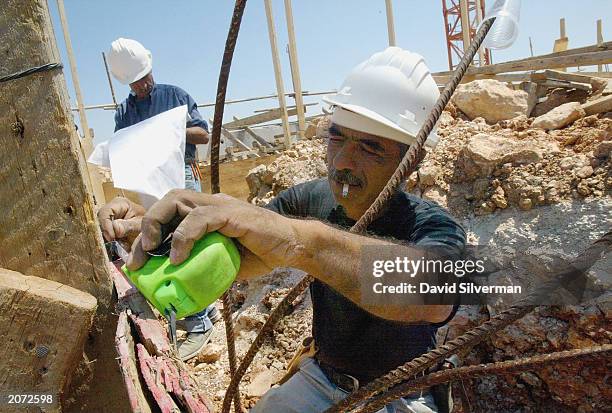 An Arab labourer prepares the foundations for a new housing project on June 11, 2003 in the West Bank Jewish settlement of Ariel. According to...