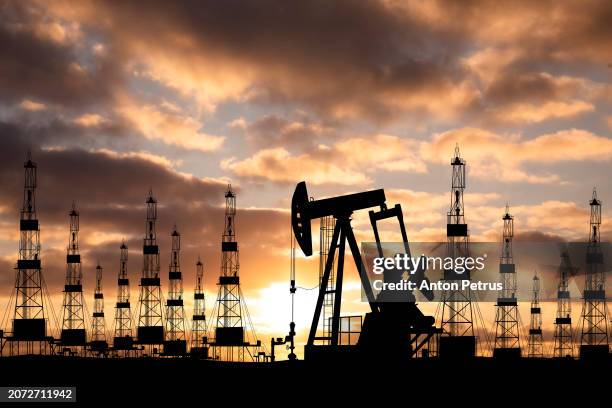 oil field with rigs at sunset. world oil industry - erdöl stock-fotos und bilder