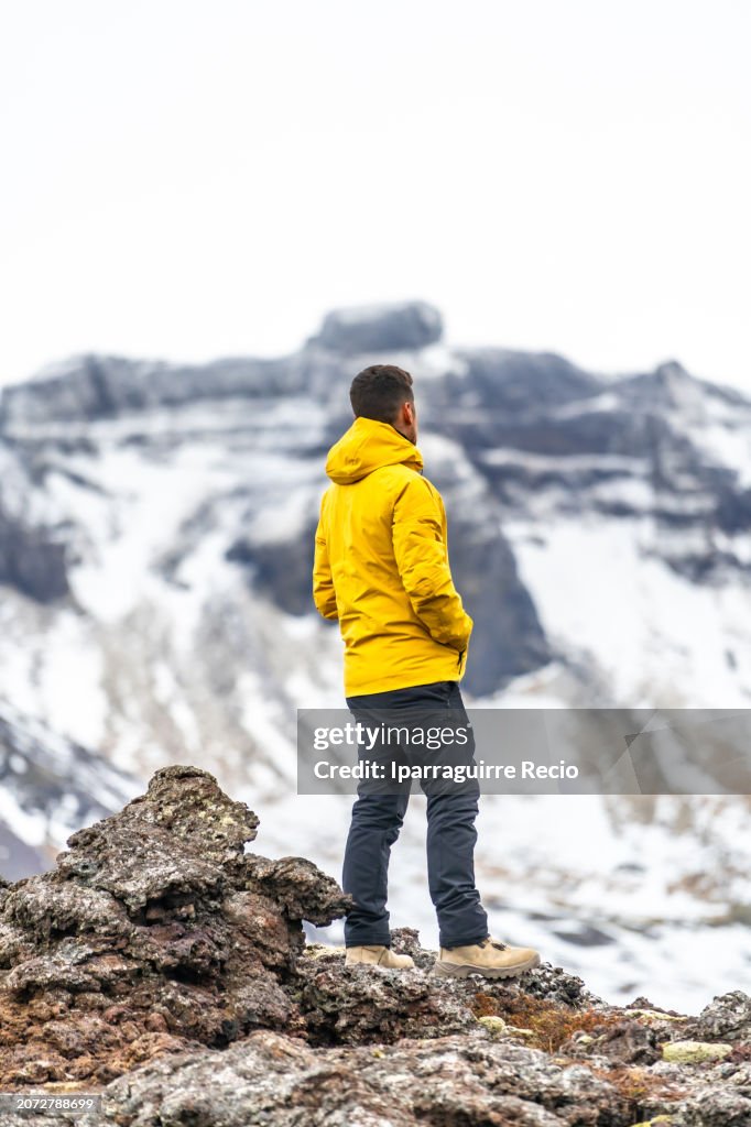 Man looking at a snowy volcano crater