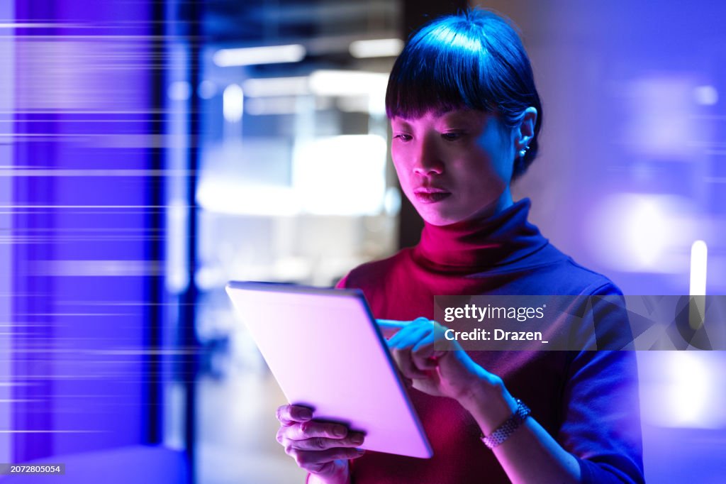 Futuristisches Büro mit asiatischer reifer Geschäftsfrau, die digitales Tablet im Büro verwendet