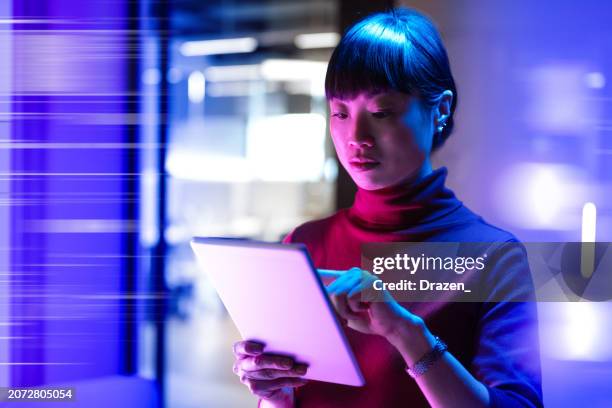 futuristic office with asian mature businesswoman using digital tablet in office - purple business stock pictures, royalty-free photos & images