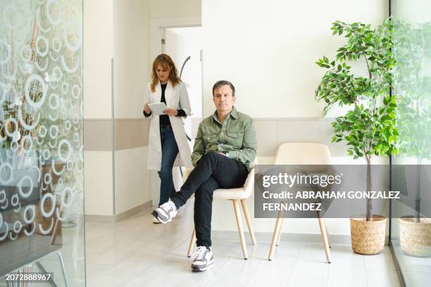 arzt, der das wartezimmer betritt, um einen patienten in einer klinik anzurufen - praxis stock-fotos und bilder