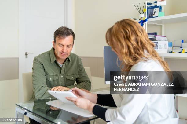 man talking to female doctor about test results - resultados de exames médicos imagens e fotografias de stock