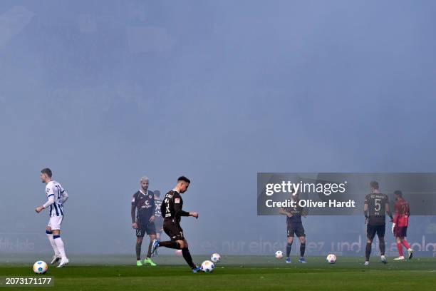 Players of FC St. Pauli and Hertha Berlin warm up as kick-off is delayed due to pyrotechnics prior to the Second Bundesliga match between FC St....