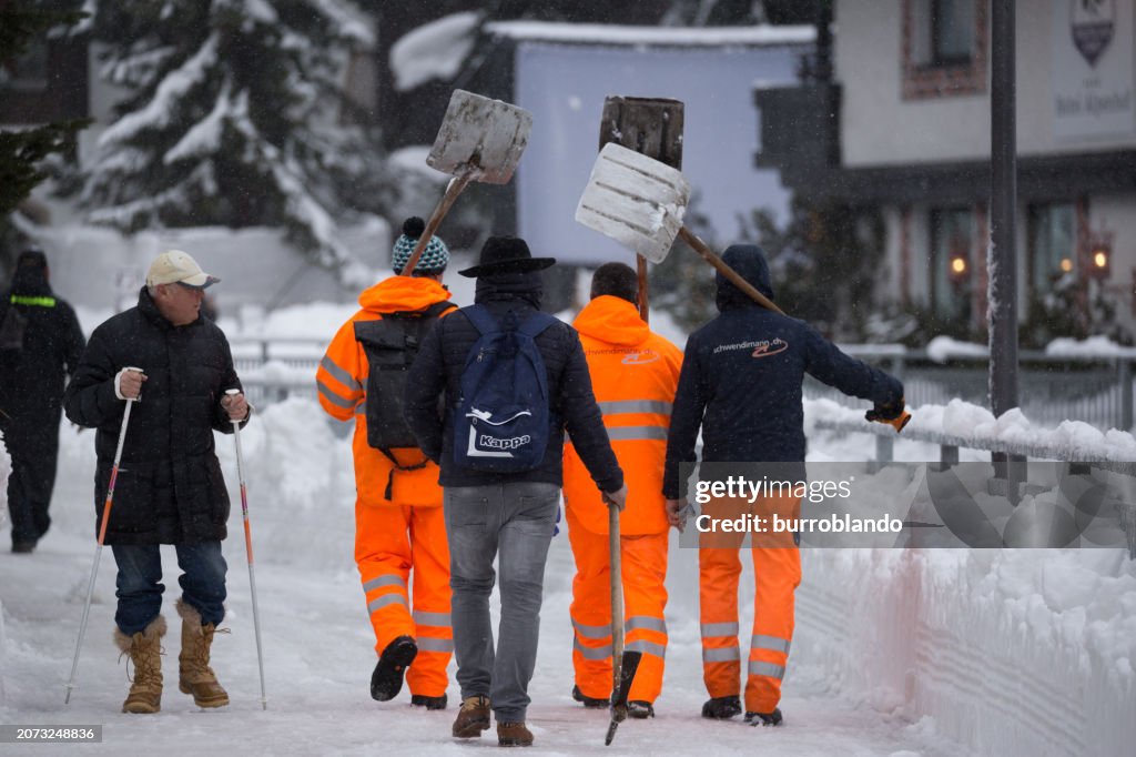 Four workers with shovels make their way down the road after a night of heavy snow helping to clear the paths of Zermatt