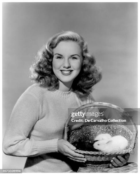 Publicity portrait of Canadian actor and singer Deanna Durbin holding a basket with bunnies in commemoration of Easter United States.