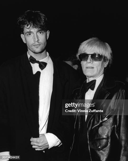 British actor Rupert Everett and American artist Andy Warhol attend Swifty Lazar's Oscar Party, held at Spago, a restaurant on the Sunset Strip in...