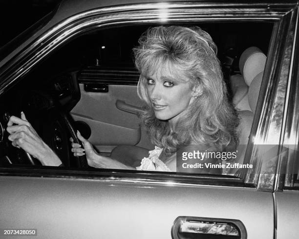 Headshot of American actress Morgan Fairchild, in the window of the car she is driving, United States, circa 1983.