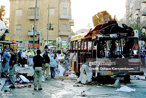Emergency workers surround the wreckage of a bus after a suicide bomber blew himself up on the bus June 11, 2003 in Jerusalem, Israel. The blast left...