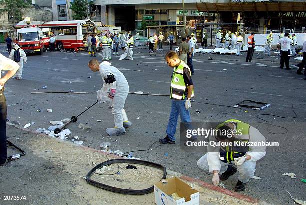 Orthodox Jewish aid workers and policemen clean up blood and look for body parts next to the wreckage of a bus after a suicide bomber blew himself up...