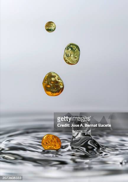 natural water surface with a group of golden liquid drops falling and splashing. - bernat bacete stock pictures, royalty-free photos & images