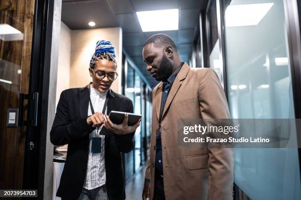 coworkers using digital tablet in the corridor hallway - employee badge stock pictures, royalty-free photos & images
