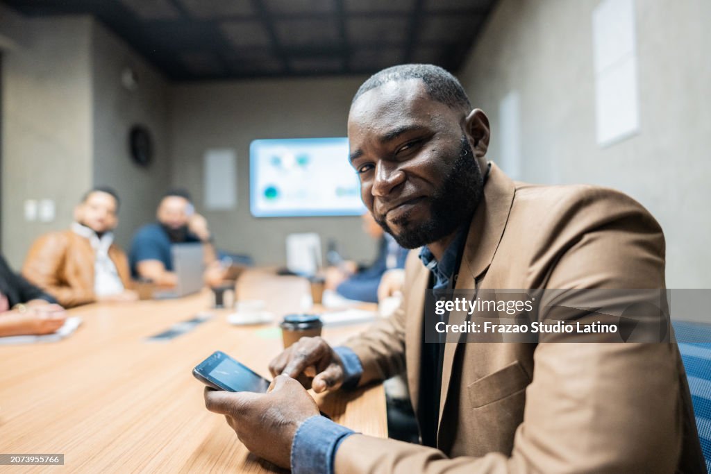 Portrait of a mature businessman using mobile phone in the meeting room