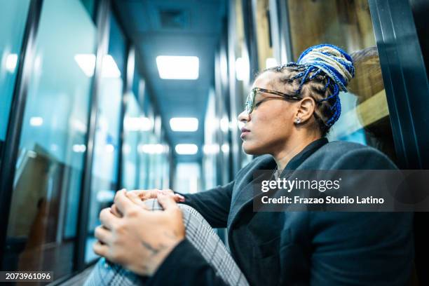 besorgte geschäftsfrau sitzt auf dem boden im büroflur - dominikanischer abstammung stock-fotos und bilder